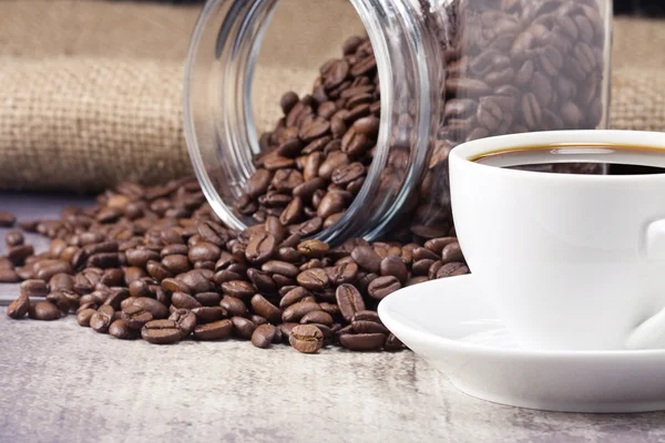Xícara de café e panela cheia de grãos no saco — Fotografia de Stock