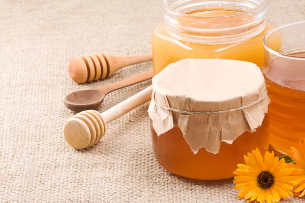 Glass pot with honey on sack — Stock Photo, Image