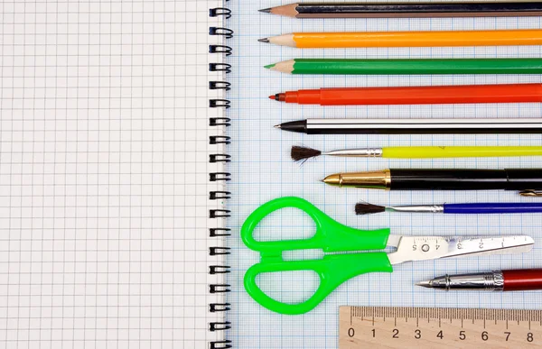 Bolígrafos, lápices y tijeras sobre papel cuadrícula gráfico — Foto de Stock