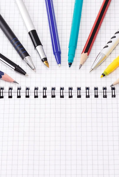 Pens and pencils on notebook — Stock Photo, Image
