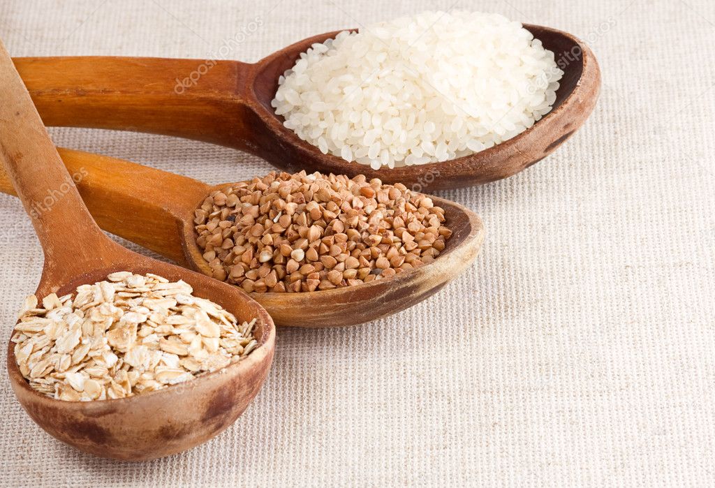 Oat, rice and buckwheat in wood spoon on sack