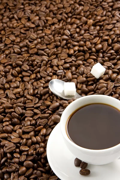 Kopp kaffe och sked på rostade bönor — Stockfoto