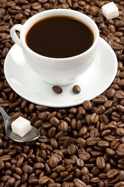 Tasse Kaffee und Löffel auf gerösteten Bohnen — Stockfoto