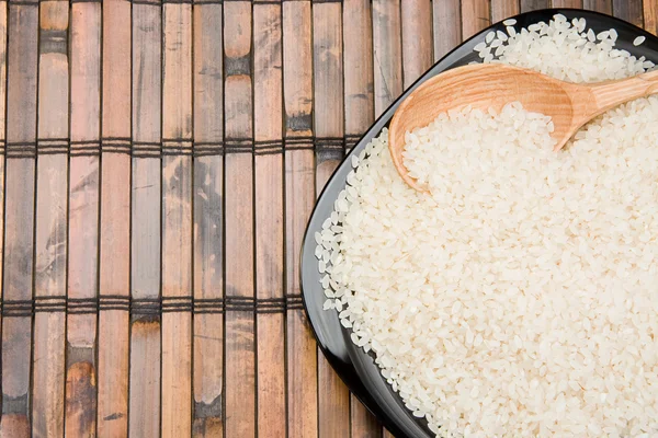 Reis- und Holzteller mit Löffel auf Tisch — Stockfoto
