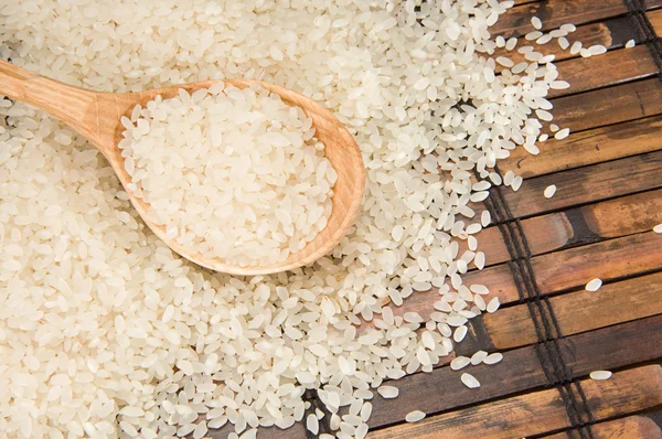 Pirinç ve tahta kaşık masa üzerinde — Stok fotoğraf