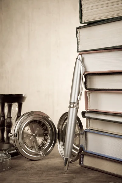 ペンとウッドの背景に本の山 — ストック写真