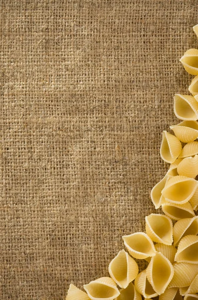 Ruwe pasta op zak Hessiaan achtergrond — Stockfoto
