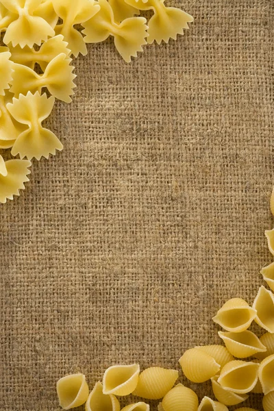 Rå pasta på säck hessian bakgrund — Stockfoto