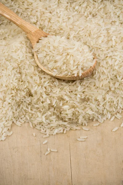 Sementes de arroz não cozidas e colher de madeira — Fotografia de Stock