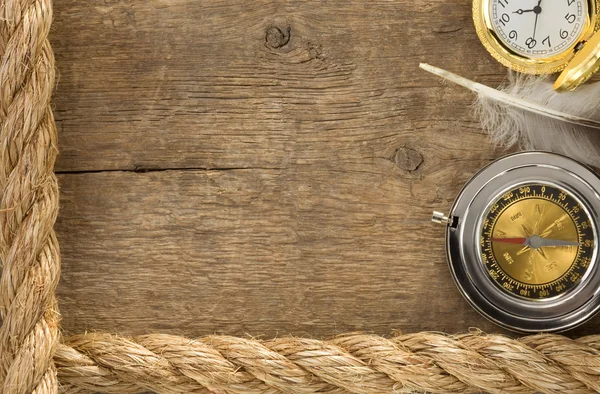 Ship ropes and compass with feather at old wood — Stock Photo, Image