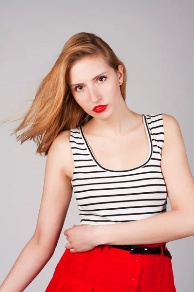 stock image Attractive lady in red skirt and striped t-shirt on grey background