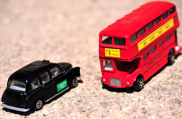 En ljus röd traditionell london buss och svart taxi isolerade över tjära-seal. — Stockfoto