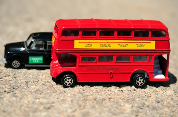 A bright red traditional London Bus and Black Taxi isolated over tar-seal. — Stock Photo, Image