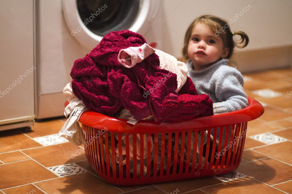 Mujer sonriente que sostiene la cesta y que cuelga la ropa con las