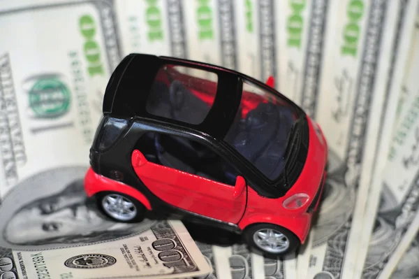 Zwarte en rode auto over een heleboel dollarbiljetten geïsoleerd op wit (selectieve aandacht) — Stockfoto