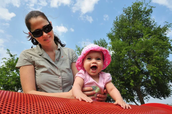 Baby flicka leker med mamma på lekplats — Stockfoto