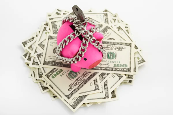 Chained piggy bank on pile of dollars — Stock Photo, Image