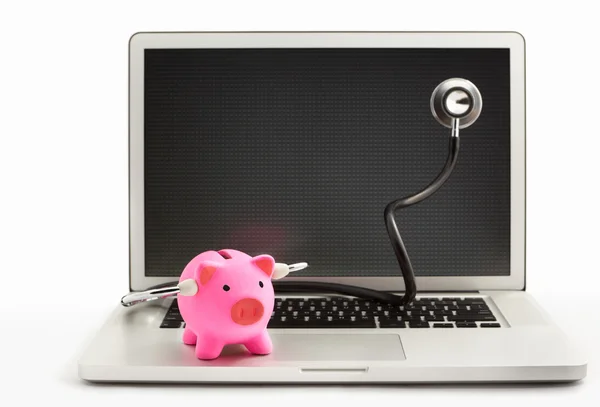 Banco porquinho com estetoscópio no laptop — Fotografia de Stock