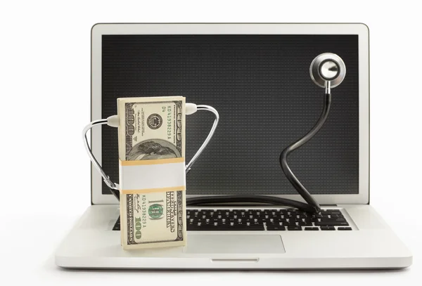 Stapel dollarbiljetten met stethoscoop op laptop — Stockfoto