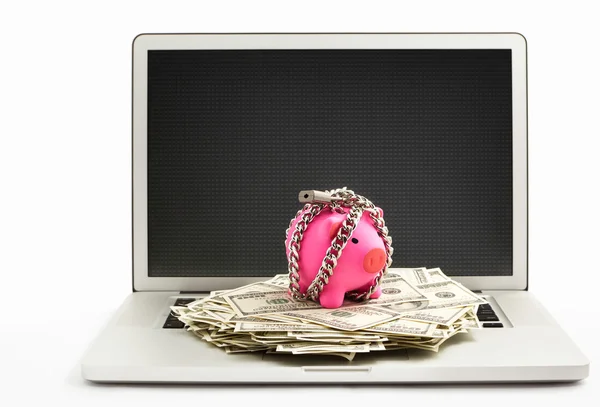 Chanined piggy bank and dollar on laptop — Stock Photo, Image