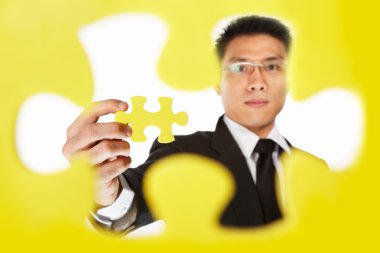 Businessman holding the last piece of puzzle clipart