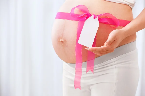 Pink ribbon arround pregnant lady's stomach — Stock Photo, Image