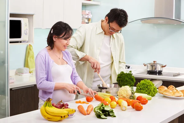 Asian couple busy in kitchen — Stock Photo, Image