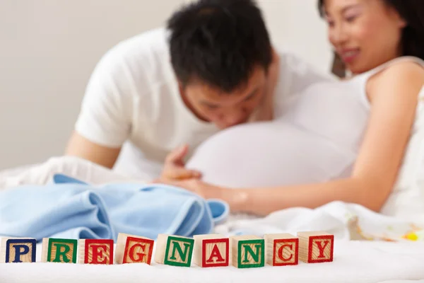 Palavra gravidez na frente de casal feliz — Fotografia de Stock
