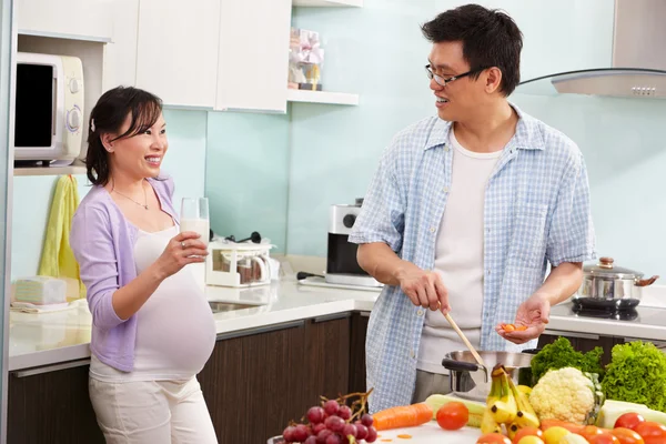 Pregnant wife drinking milk watching her husband — Stock Photo, Image