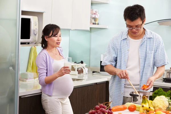Pregnant wife drinking milk watching her husband — Stock Photo, Image