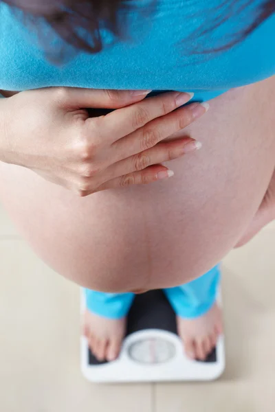 Senhora grávida medindo seu peso — Fotografia de Stock