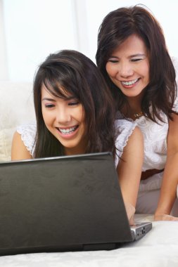 Mother and daughter using laptop clipart