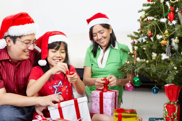 和父母一起打开圣诞礼物的小女孩 免版税图库照片