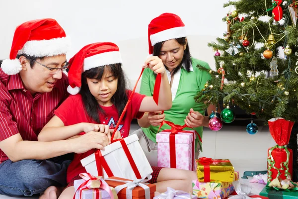 和父母一起打开圣诞礼物的小女孩 图库图片