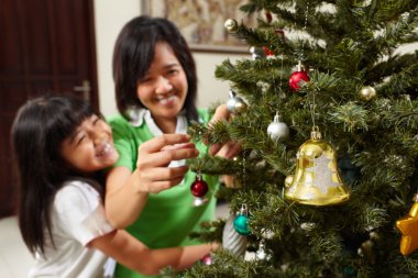 Asian mother and daughter decoarting Christmas tree clipart