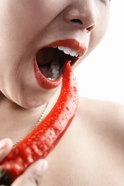Mulher segurando grande pimenta vermelha na frente de sua boca — Fotografia de Stock