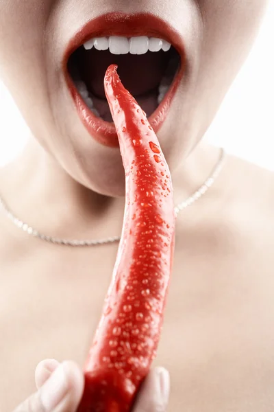 Mujer sosteniendo chile rojo grande delante de su boca — Foto de Stock