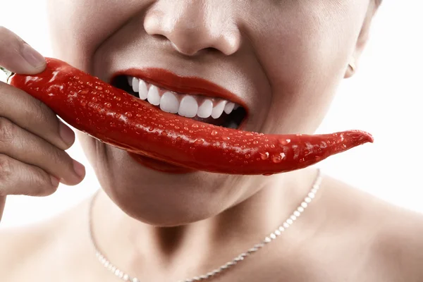 Vrouw met grote rode chili tegenover haar mond — Stockfoto