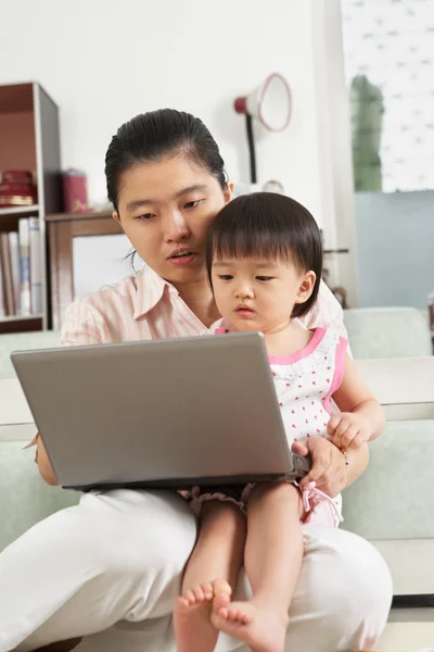 Mother and daughter playing laptop together — Stock Photo, Image