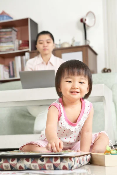 Маленькая девочка играет, пока ее мать работает — стоковое фото