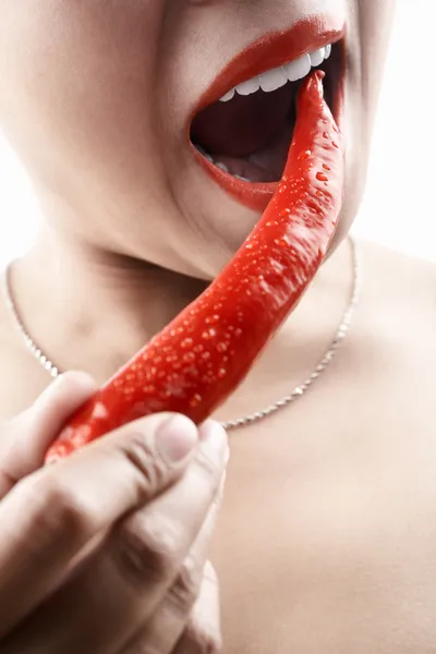 Donna che tiene grande peperoncino rosso davanti alla bocca — Foto Stock