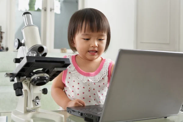 Ιδιοφυΐα κορίτσι litlle με φορητό υπολογιστή και μικροσκόπιο — Φωτογραφία Αρχείου