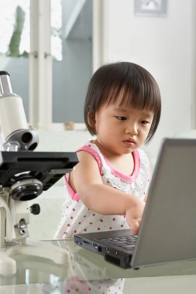 Menina litlle gênio com laptop e microscópio — Fotografia de Stock
