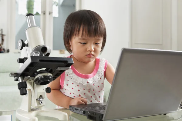 Genius litlle girl with laptop and microscope — Stock Photo, Image
