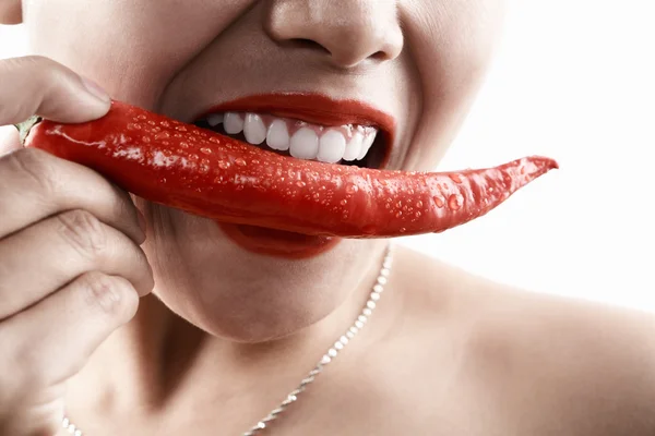 Kvinna med stor röd chili framför hennes mun Stockfoto