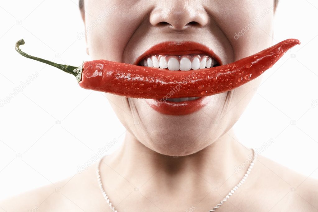 Woman holding big red chili in mouth