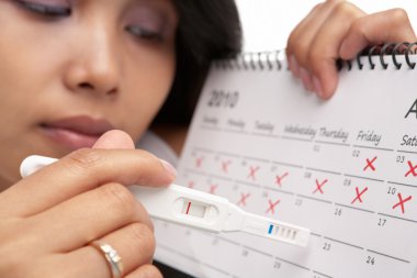 Sad woman with negative pregnancy test and calendar clipart