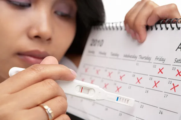Mulher triste com teste de gravidez negativo e calendário — Fotografia de Stock
