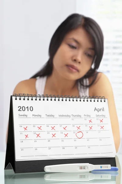 stock image Sad woman with negative pregnancy test and calendar