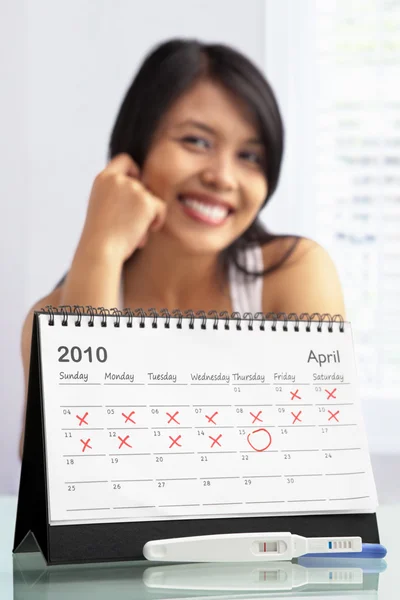 Mulher feliz com teste de gravidez positivo e calendário — Fotografia de Stock